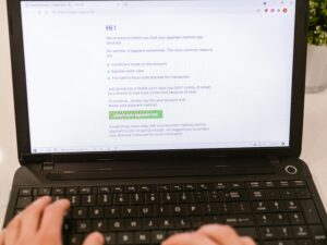Close-up of hands typing on laptop keyboard, focusing on online payment verification.